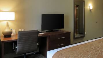 A hotel room with a desk, chair, television, and a bed.