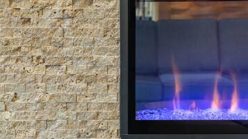 Eine Steinsäule mit einem modernen Kamin, in dem blaue Flammen lodern.