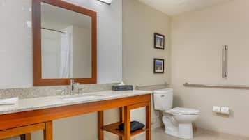 Un baño con tocador de madera, inodoro blanco, barandilla y dos cuadros en la pared.
