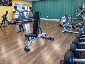 A gym with various exercise equipment, including treadmills, a bench press, and dumbbells. - Holiday Inn Express & Suites Oklahoma City Airport by IHG (Oklahoma City)