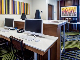 A hotel reception area with two desktop computers, a telephone, and a keyboard on a desk.