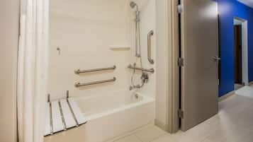 A modern bathroom with a bathtub, grab bars, and a shower.
