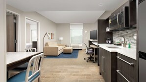 Una habitación de hotel moderna con kitchenette, comedor y sala de estar.