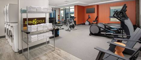 A gym with exercise equipment, a laundry area, and a sign reading "SPIN2CYCLE".