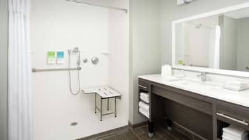Une salle de bain moderne équipée d’une douche, d’un meuble-lavabo avec miroir et d’un porte-serviettes.