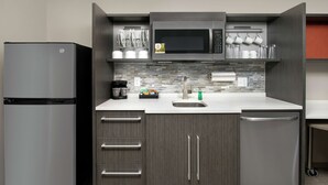 Una cocina moderna con un refrigerador de acero inoxidable, un microondas, una cafetera y un lavavajillas.