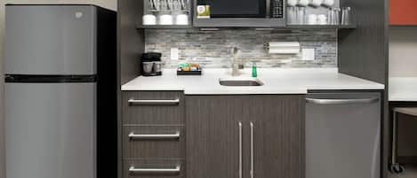 Una cocina moderna con un refrigerador de acero inoxidable, un microondas, una cafetera y un lavavajillas.