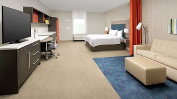 A hotel room with a desk, a bed, a sofa, and a TV.
