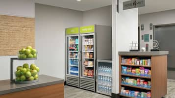 A hotel lobby with a reception desk, two beverage dispensers labeled 'cold' and 'really cold', and a display case with snacks and bottled water.