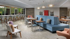 Un moderno vestíbulo de hotel con una variedad de opciones de asientos, incluyendo un sofá azul, sillas y mesas.