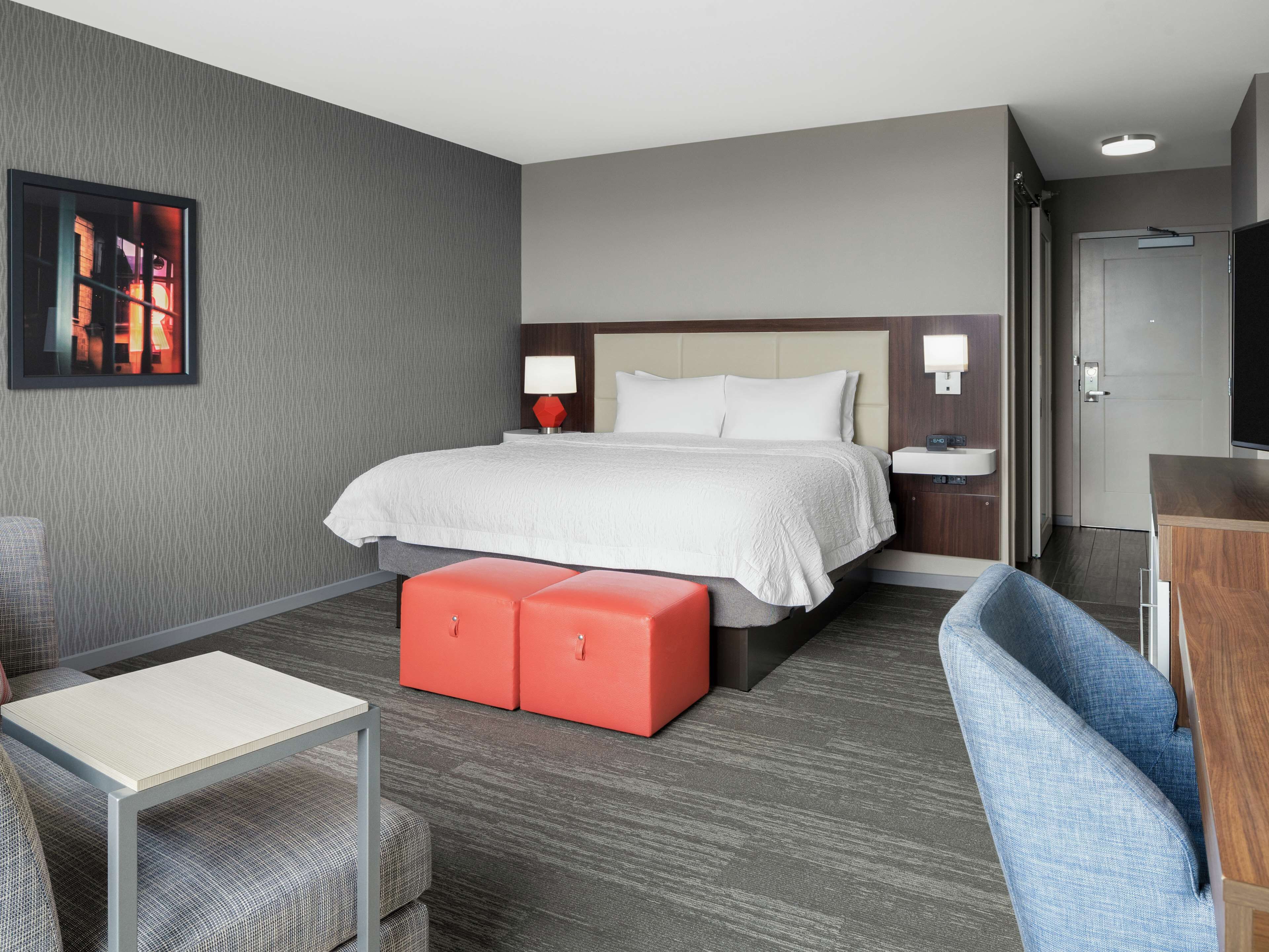 A hotel room with a large bed, a desk, a chair, and a TV.