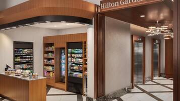 Hall d'albergo con reception, distributori automatici e ascensore.