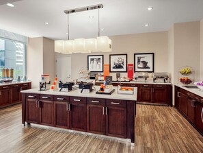 A modern kitchen with a central island, built-in cabinets, and a large window.