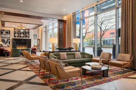 A lobby with a fireplace, seating area, and large windows offering a view of the outside.. Hampton Inn Chicago McCormick Place