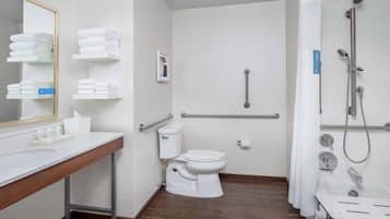 A modern bathroom with a toilet, sink, and shower. It includes grab bars and a towel rack.