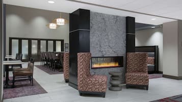 A lobby with a fireplace, seating area, and a dining section.