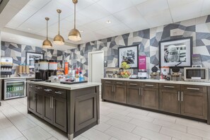 A modern kitchen with a central island, built-in appliances, and a patterned backsplash.