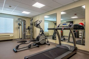 Une salle de sport équipée de tapis de course, de vélos elliptiques et de matériel de musculation.