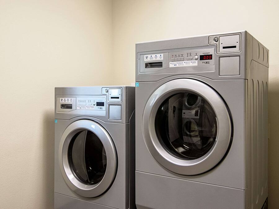 Two front-loading washing machines in a corner with a plain wall.