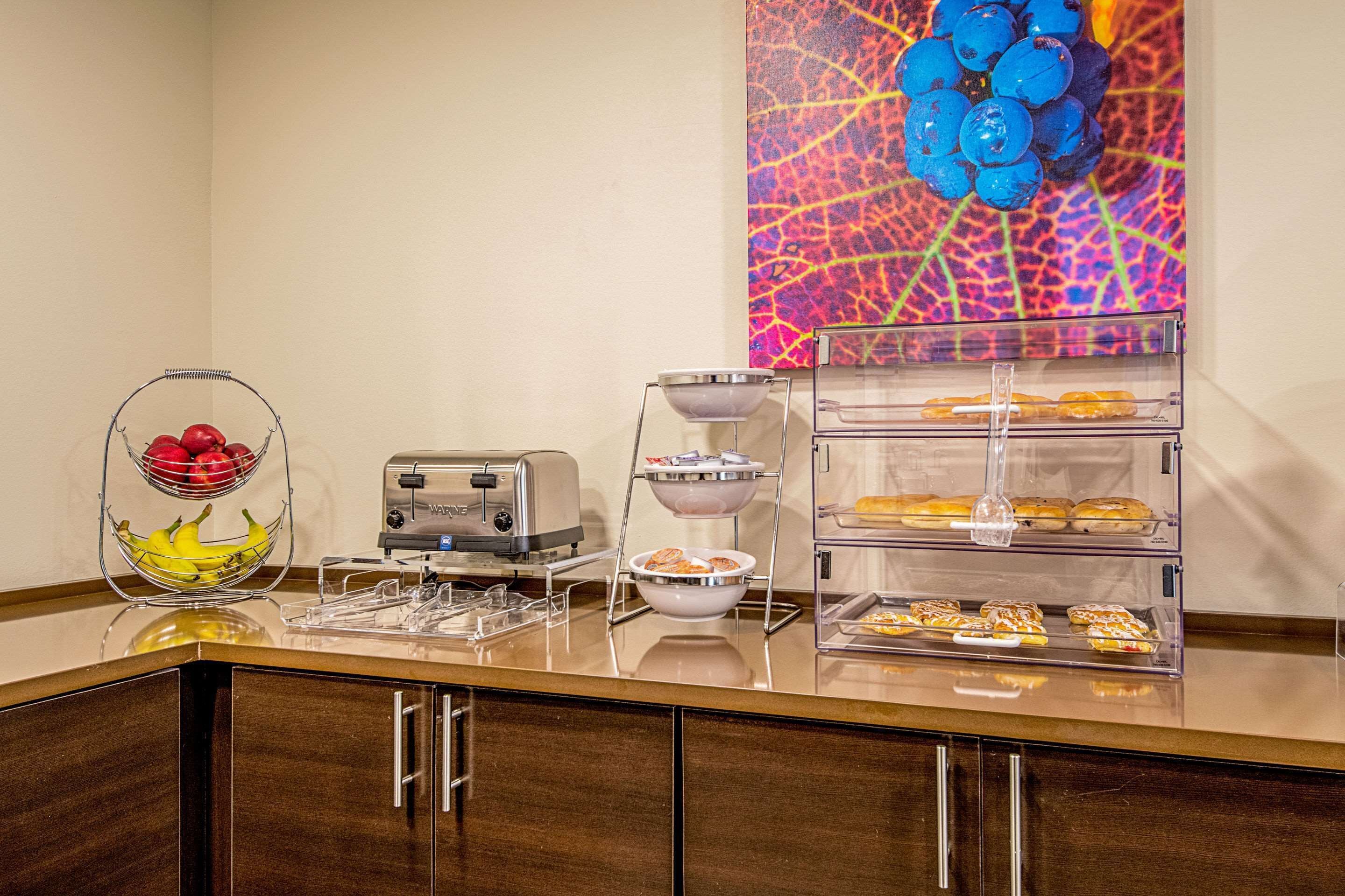 Ein Frühstücksbuffet mit verschiedenen Speisen, einem Toaster und einer Wand mit einer Obstdekoration.