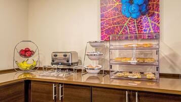 Ein Frühstücksbuffet mit verschiedenen Speisen, einem Toaster und einer Wand mit einer Obstdekoration.