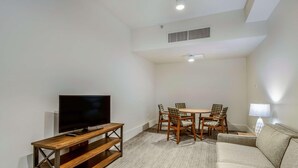 A living room with a TV, wooden furniture, a sofa, and a dining table with chairs.