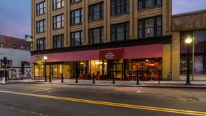 A hotel with a red awning, multiple windows, and outdoor seating.