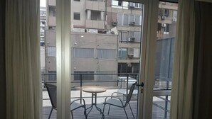 A balcony with a table and chairs, a view of a residential building with balconies and air conditioning units. - Olmos Suites (Córdoba)