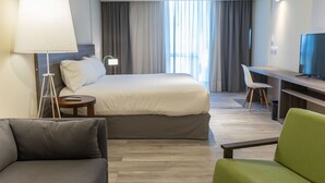 A hotel room with a bed, a desk, a television, a lamp, and a chair. - Olmos Suites (Córdoba)