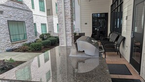 Une façade en pierre, une porte en verre et un espace détente avec des chaises.