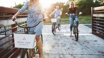 A person on a bicycle with a basket labeled "HOTEL TRIO" and "HEALDSBURG, CA."