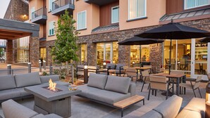 An outdoor seating area with a fire feature, cushioned seating, and umbrellas. - Hotel Trio Healdsburg (Healdsburg)