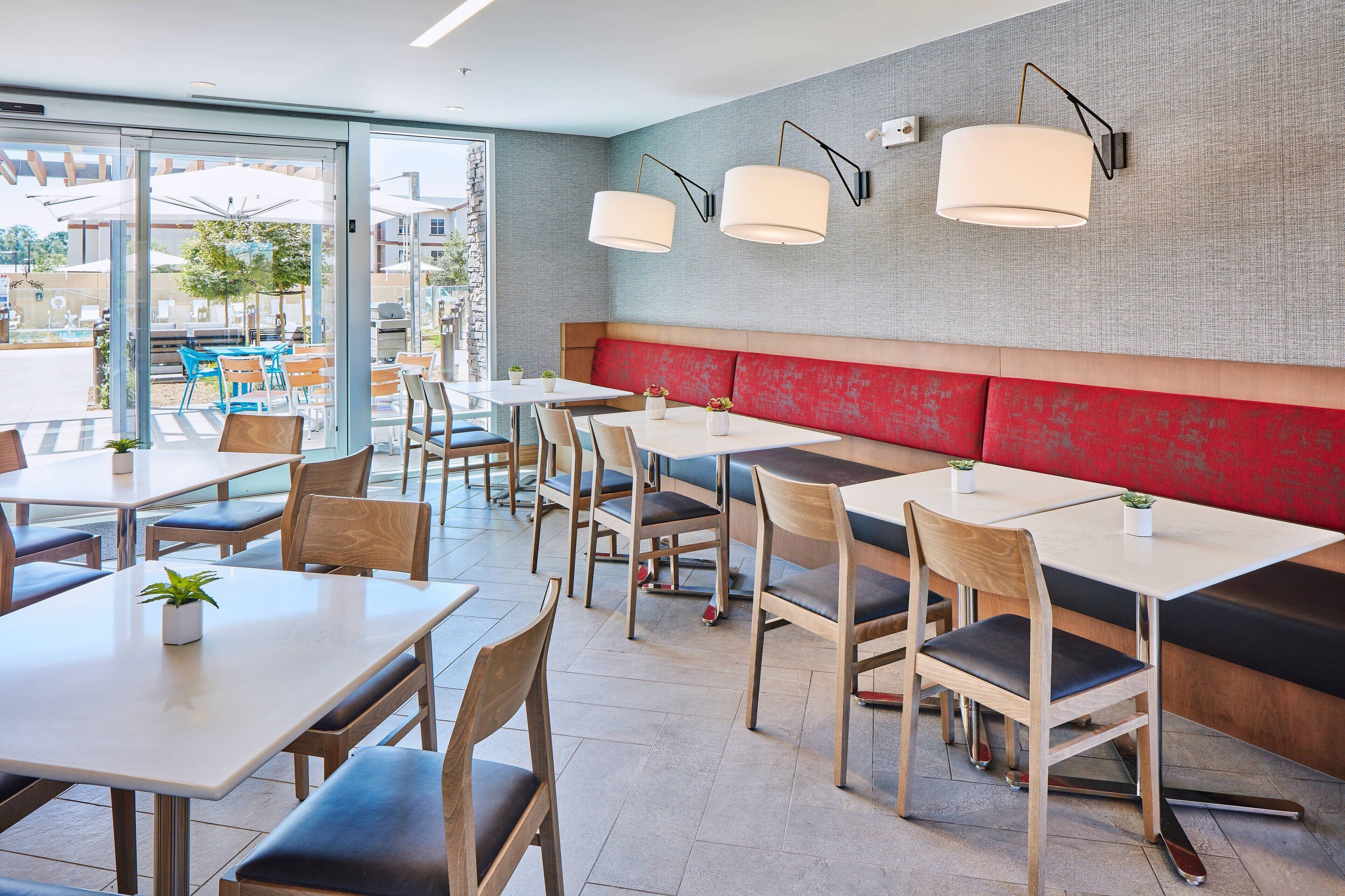 Un restaurante moderno con mesas, sillas y un banco acolchado rojo para asientos interiores.
