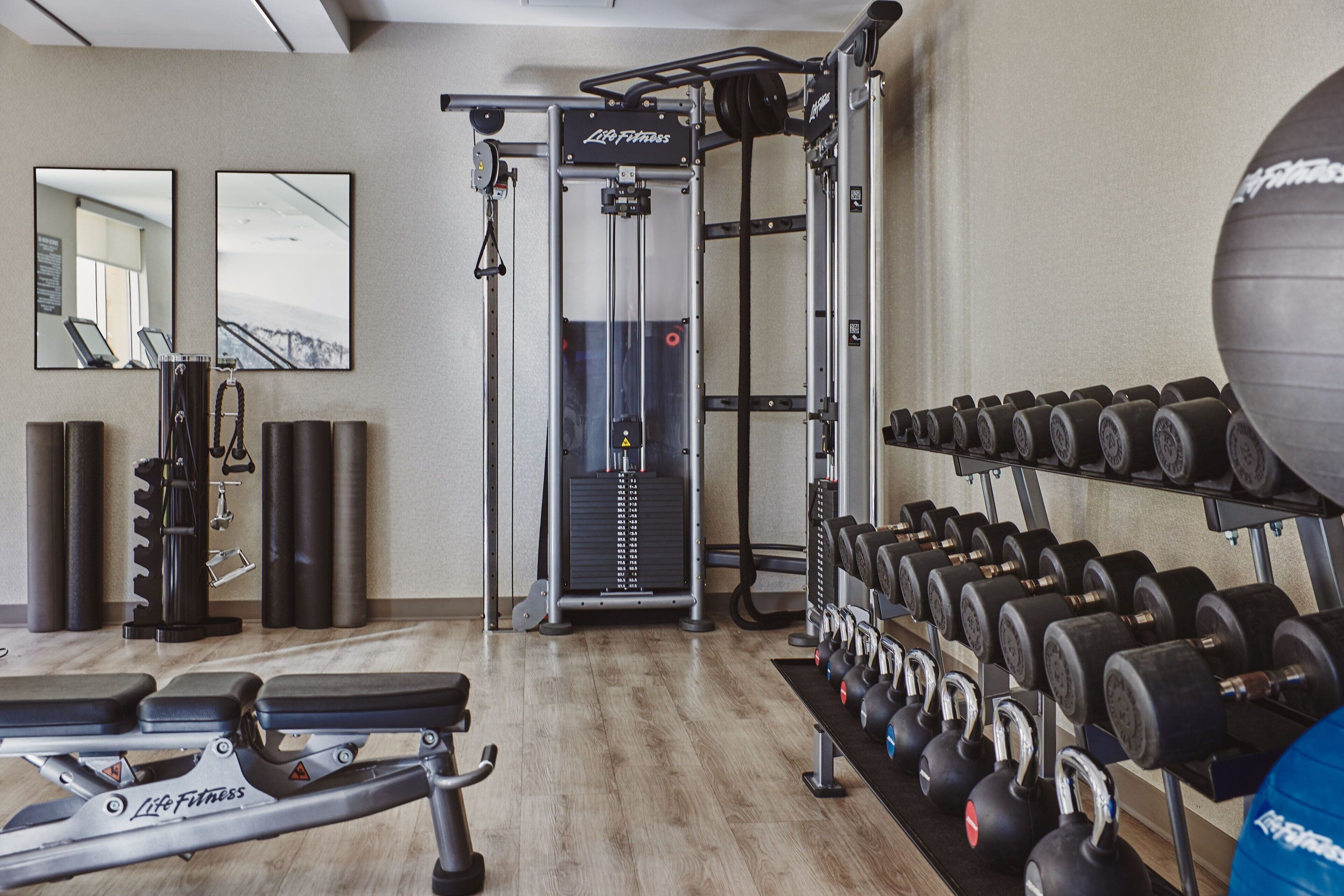 Un gimnasio con equipo de levantamiento de pesas, una banca y un espejo.