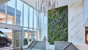 A modern hotel lobby with a reception desk, large windows, a green vertical garden, and a marble wall. - Hotel Trio Healdsburg (Healdsburg)