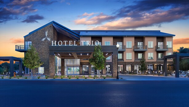 A hotel with a modern design, featuring a prominent entrance, multiple balconies, and a well-maintained outdoor area with trees and seating. - Hotel Trio Healdsburg (Healdsburg)