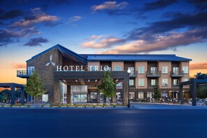 A hotel with a modern design, featuring a prominent entrance, multiple balconies, and a well-maintained outdoor area with trees and seating. - Hotel Trio Healdsburg (Healdsburg)