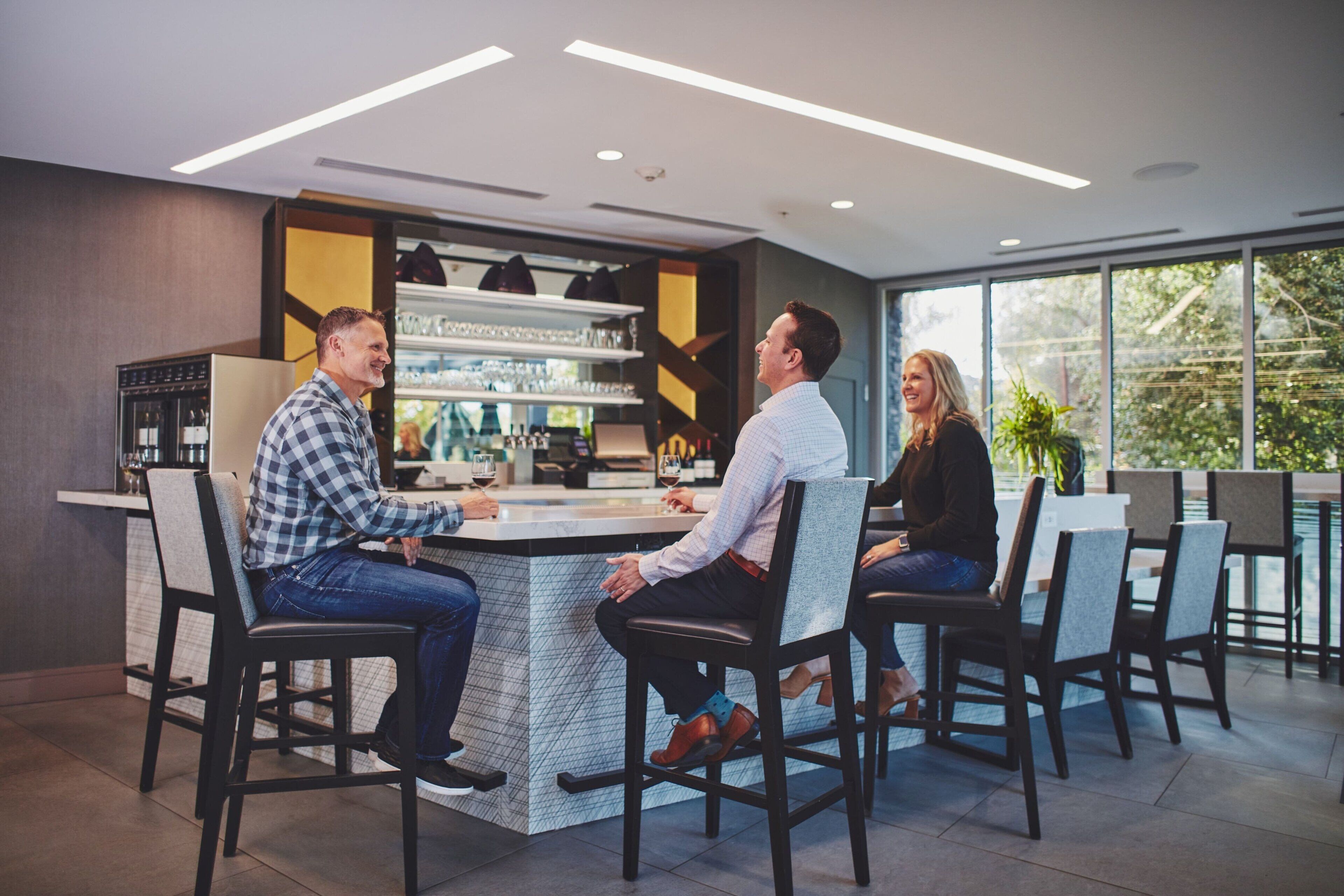A modern bar area with a counter, bar stools, and a wine rack.