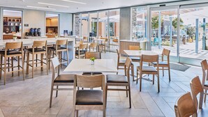 A modern cafe with wooden chairs and tables, large windows, and a view of the outdoors. - Hotel Trio Healdsburg (Healdsburg)