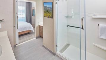 Una habitación de hotel con una cama, ducha y un cuadro de un viñedo en la pared.