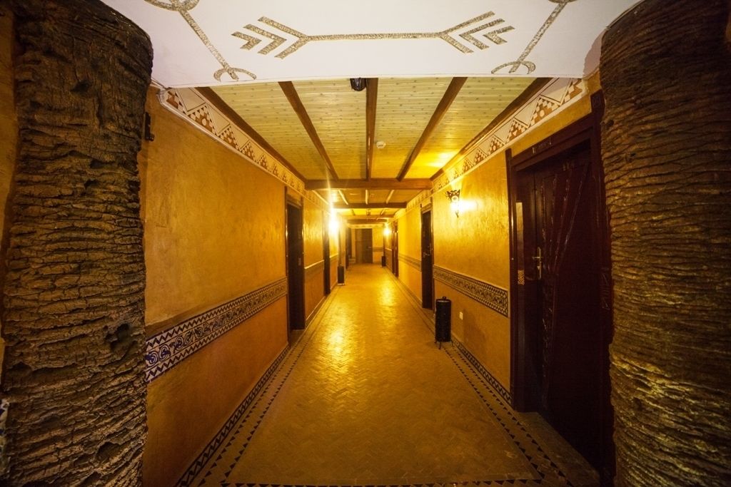 A long, narrow hallway with patterned walls and a wooden ceiling.