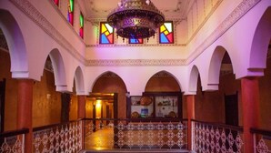 Un interior majestuoso con techos abovedados, una lámpara central y barandales con diseños.