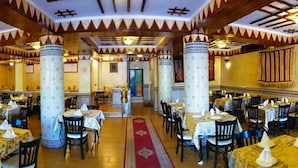 Un restaurante con mesas redondas, techos altos de madera y columnas decoradas.