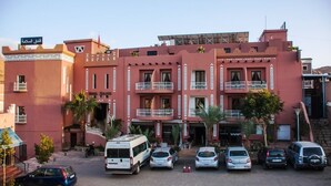 Un edificio de varios pisos con balcones, un estacionamiento y un letrero en árabe.