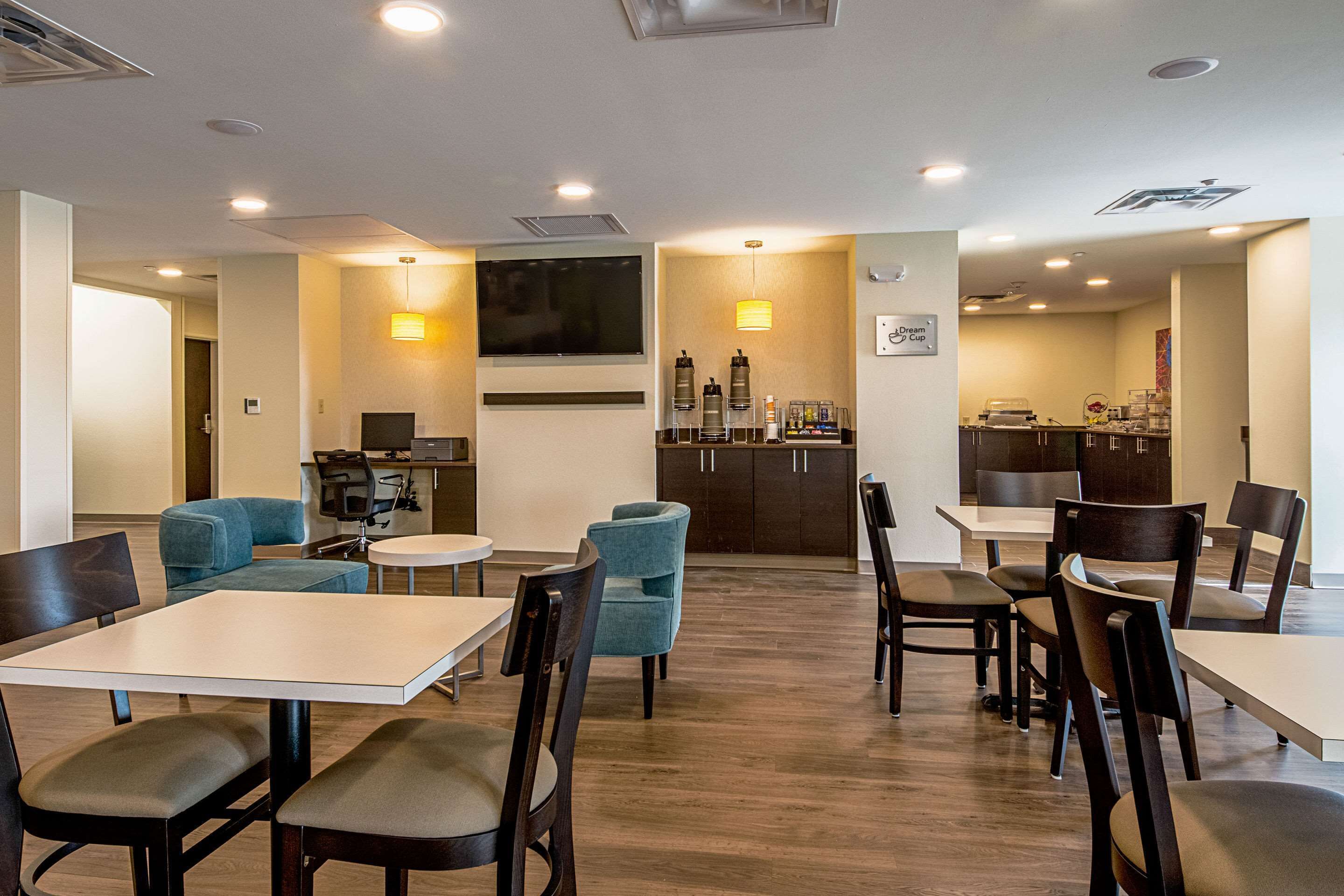 Un hall d’hôtel comprenant un bar, des espaces aménagés avec des sièges et un écran de télévision.