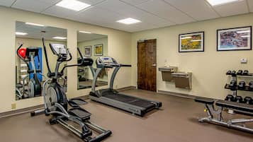 A gym with cardio machines, a treadmill, and weightlifting equipment.