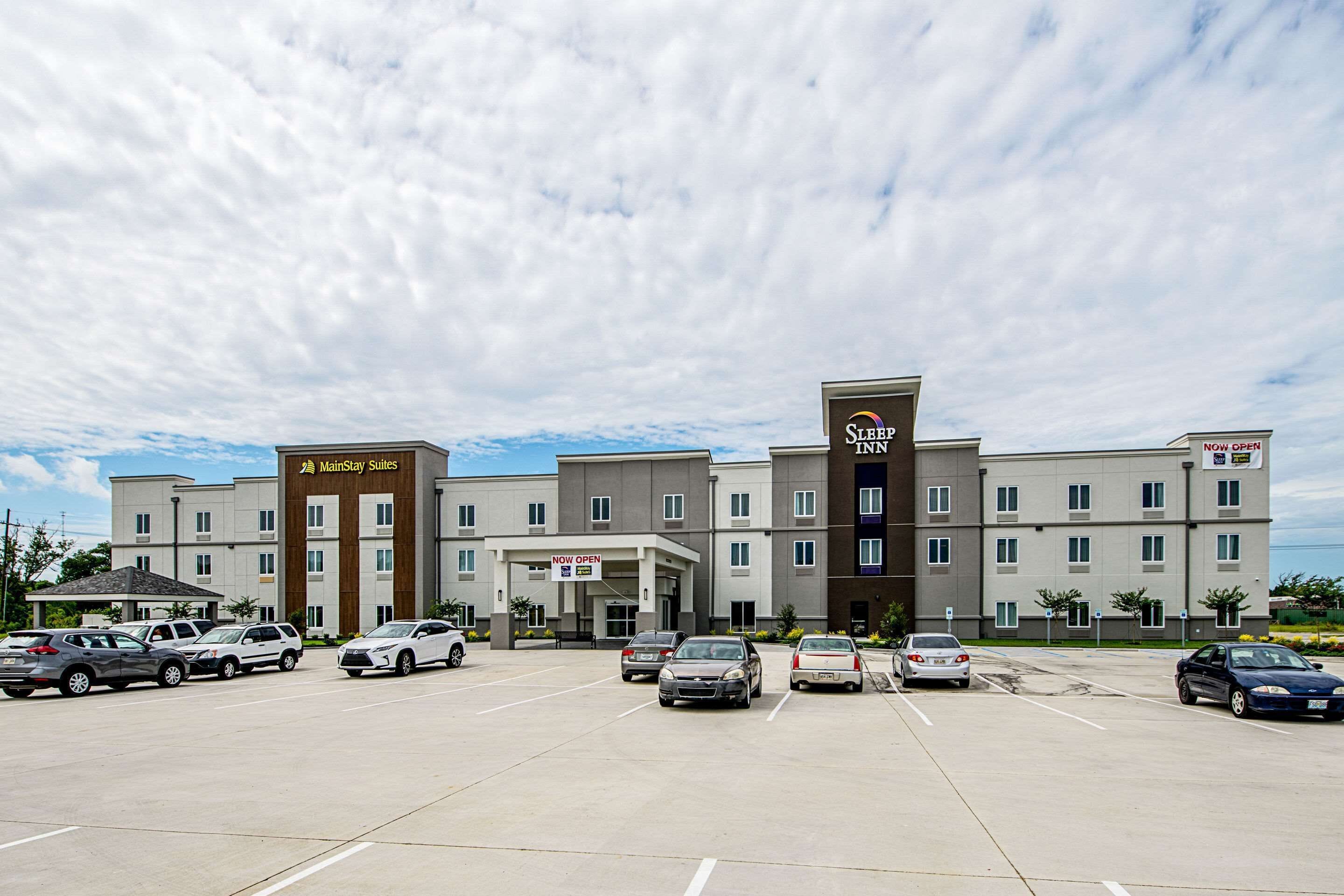 A hotel with a parking lot and multiple cars.
