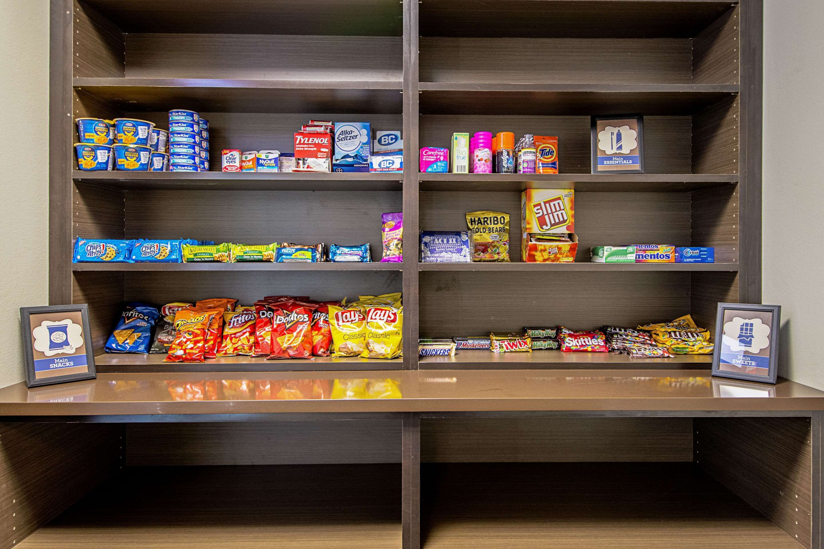 A snack shelf with various packaged snacks and a framed picture.
