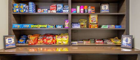 A snack shelf with various packaged snacks and a framed picture.