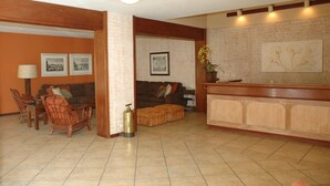 A living room with a sofa, chairs, a coffee table, a fireplace, and a wall with framed pictures. - Pousada Chablis (Campos do Jordão)